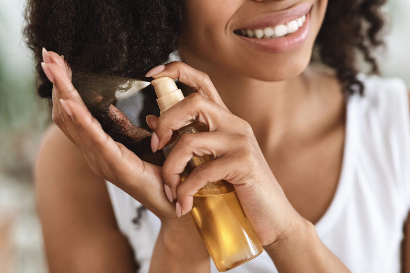 Split EAfrican Woman Applying Essential Oil Spray On Her Curly Brown hair